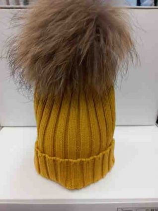 Gorro con pompóm de pelo natural en color mostaza.