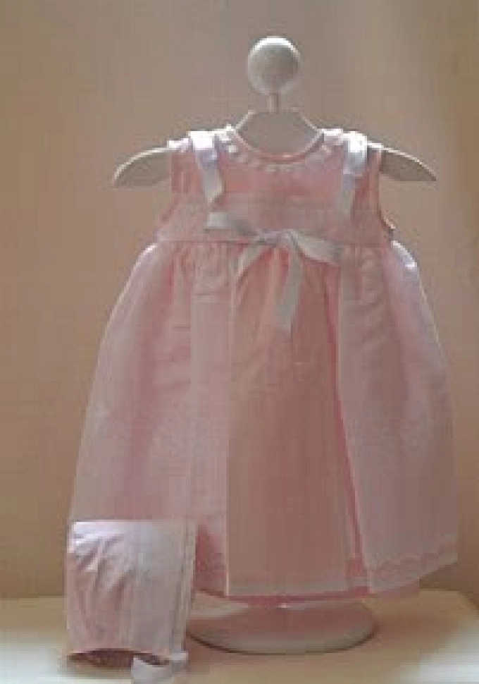 Faldón con capota rosa con tela sobrepuesta.